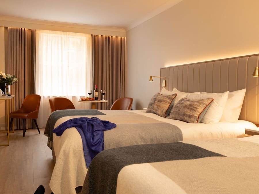A hotel room with two beds, a desk, and a chair.