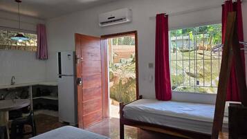 Quarto com cama, escrivaninha, pia e janela com cortinas.