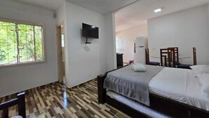 A hotel room with a bed, a TV mounted on the wall, a window, and a patterned floor. - Apartamentos Casa Da Pedra (Ubatuba)