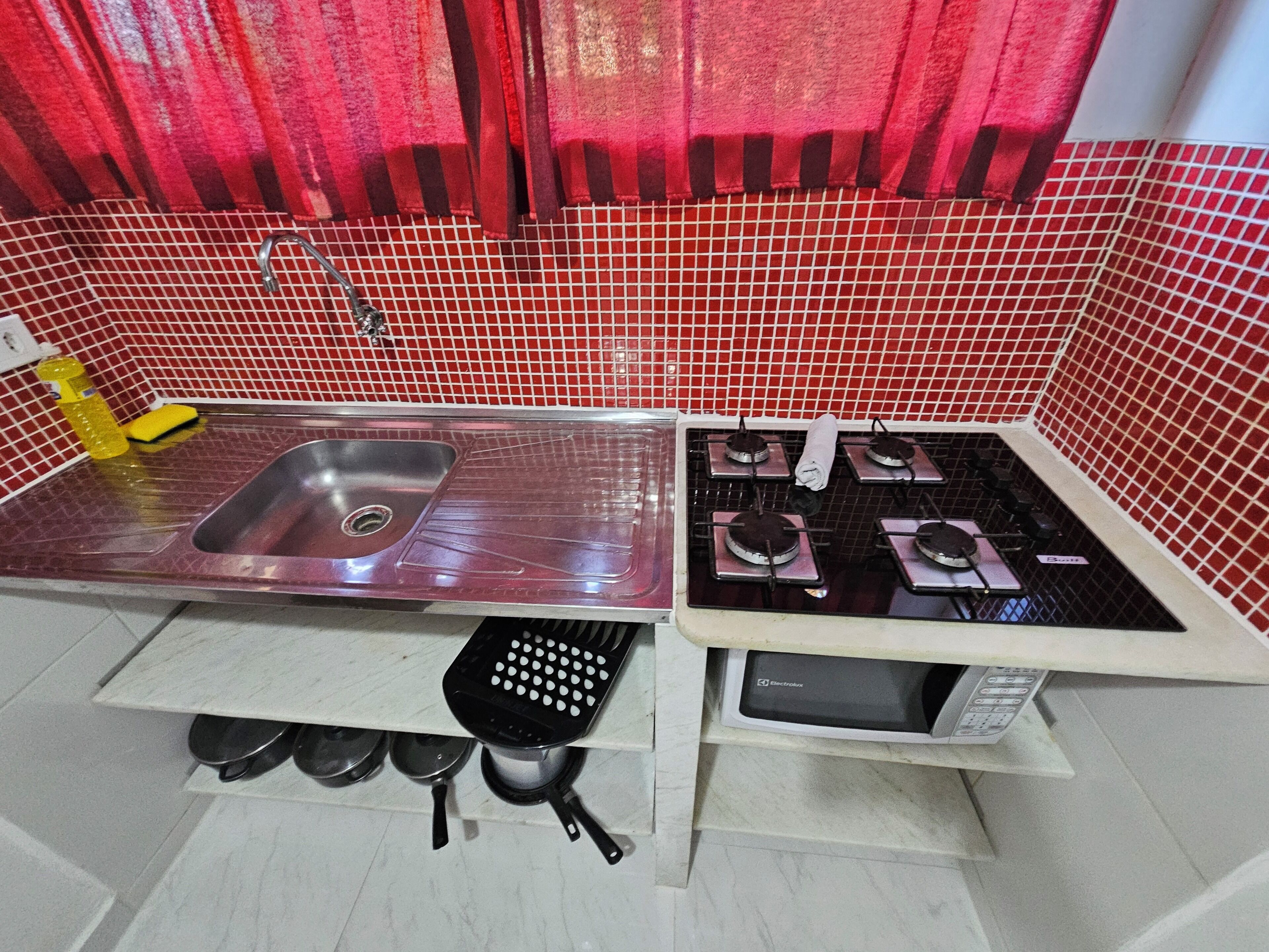 A kitchen with a stainless steel sink, a gas stove, and a microwave.