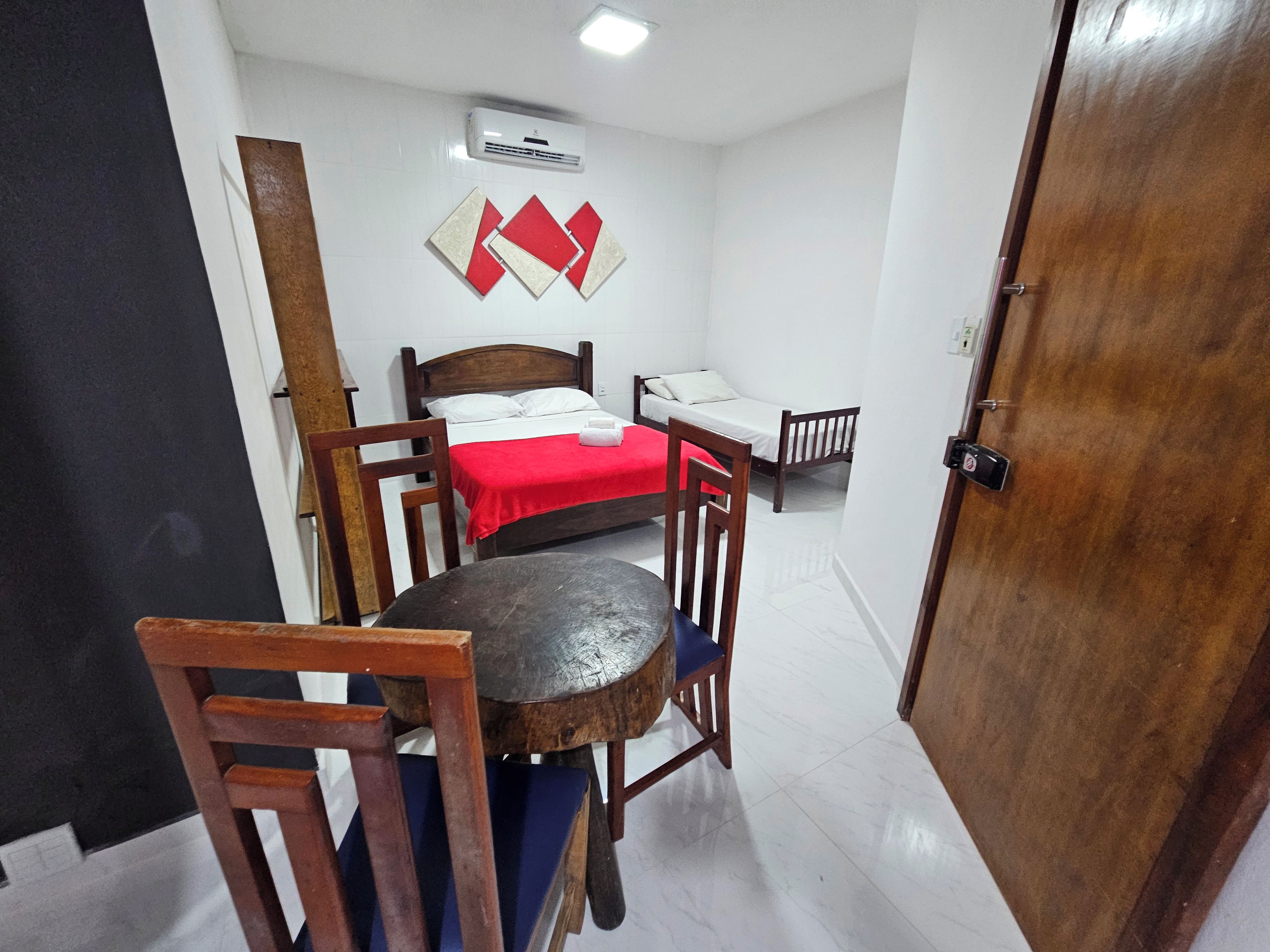 A compact room with a bed, a small table, two chairs, and a door.