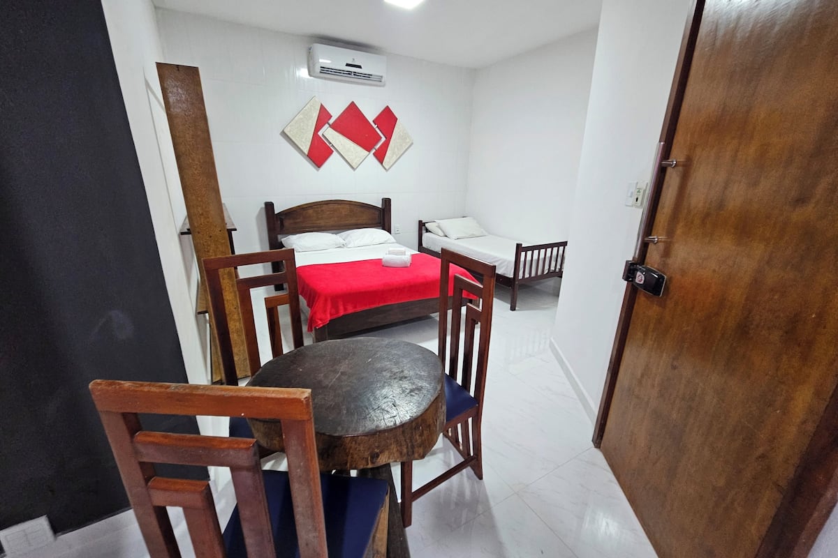 A compact room with a bed, a small table, two chairs, and a door.