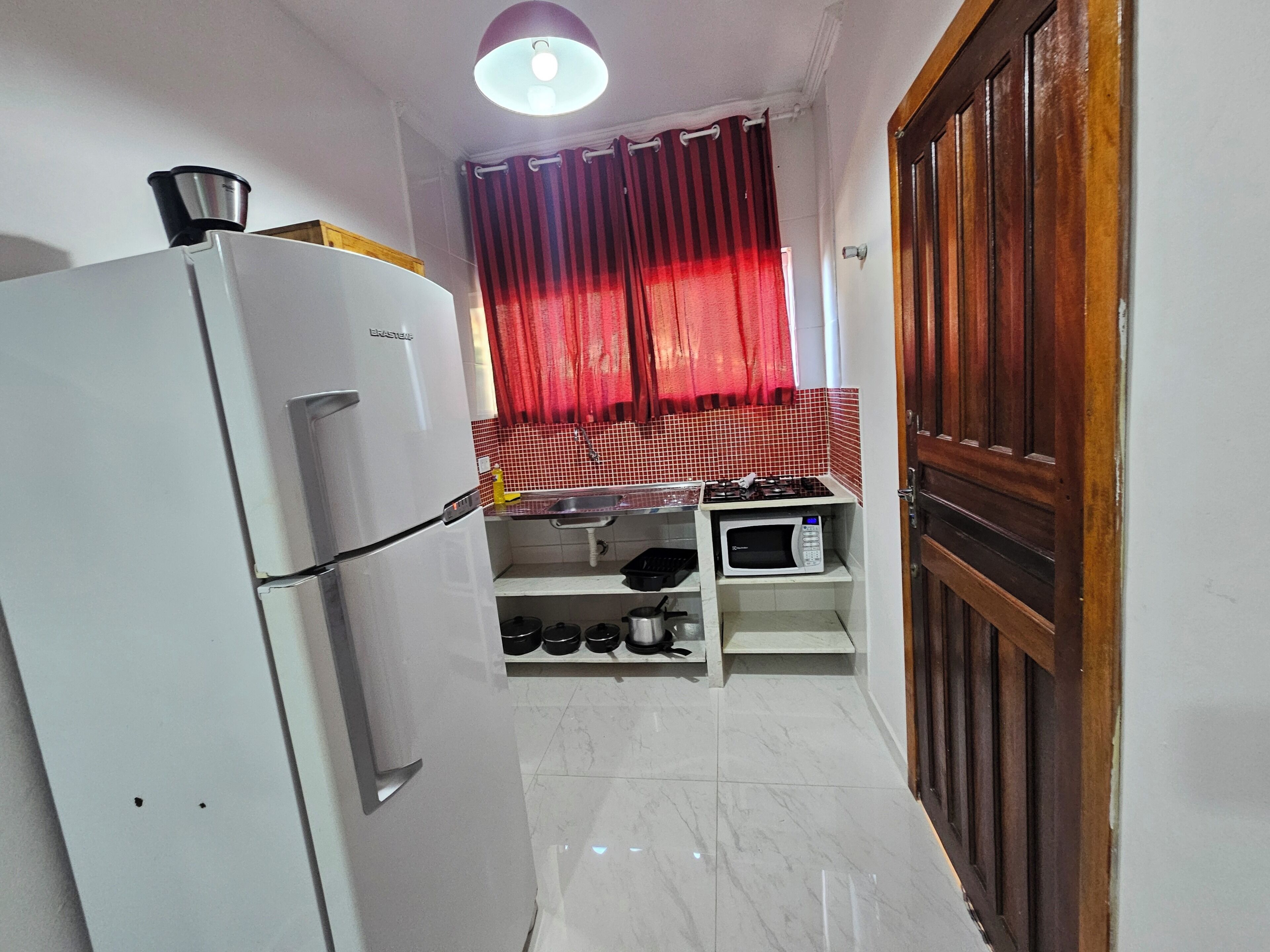 Cocina compacta con refrigerador, microondas y estufa.
