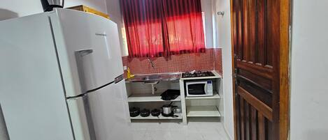 A compact kitchen with a refrigerator, microwave, and stove.