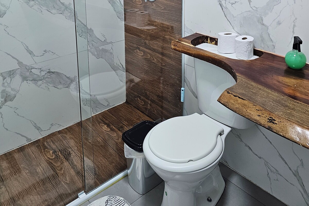 Un baño con ducha, inodoro y pared de mármol.