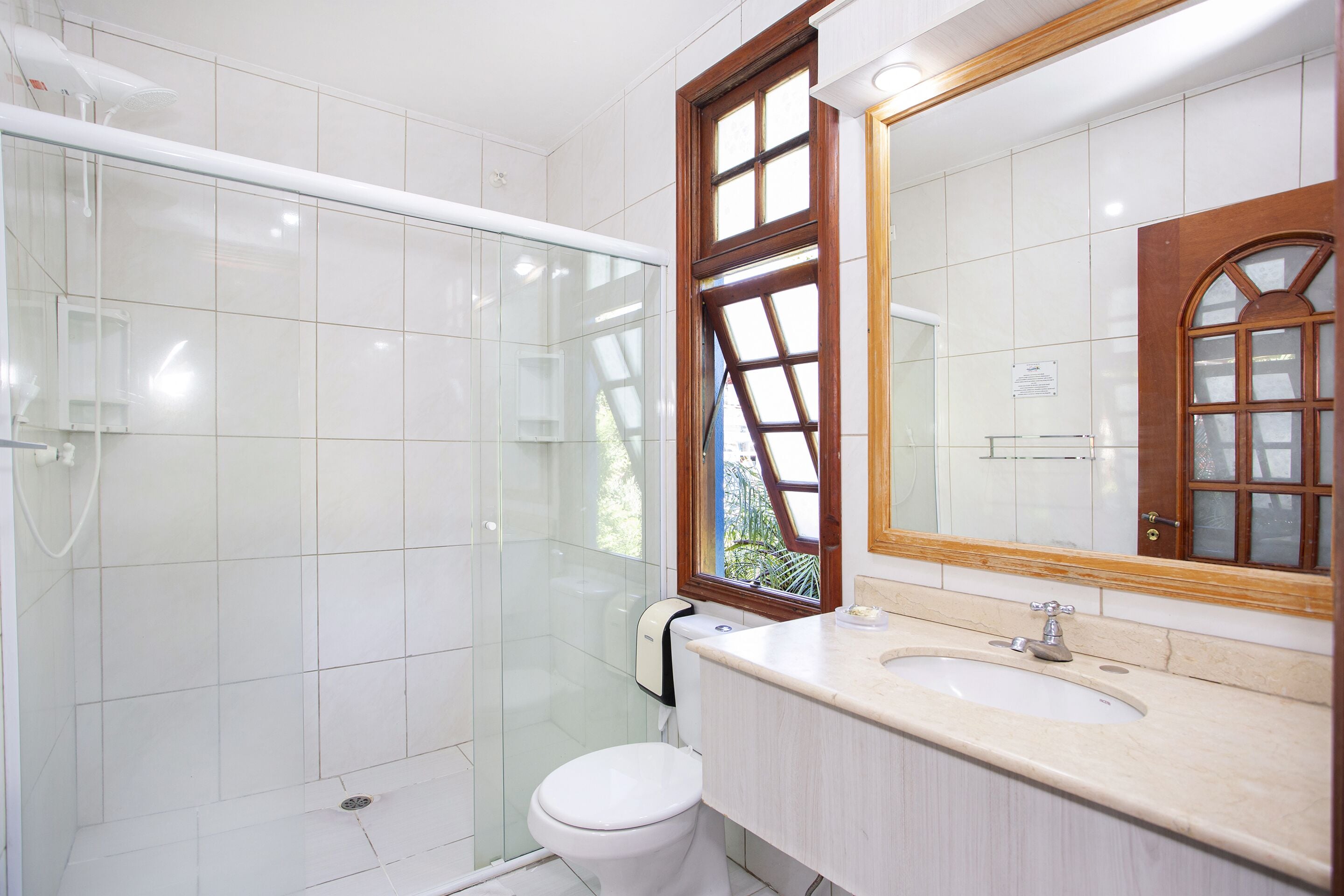 A bathroom with a glass shower enclosure, a white toilet, and a sink with a wooden vanity.