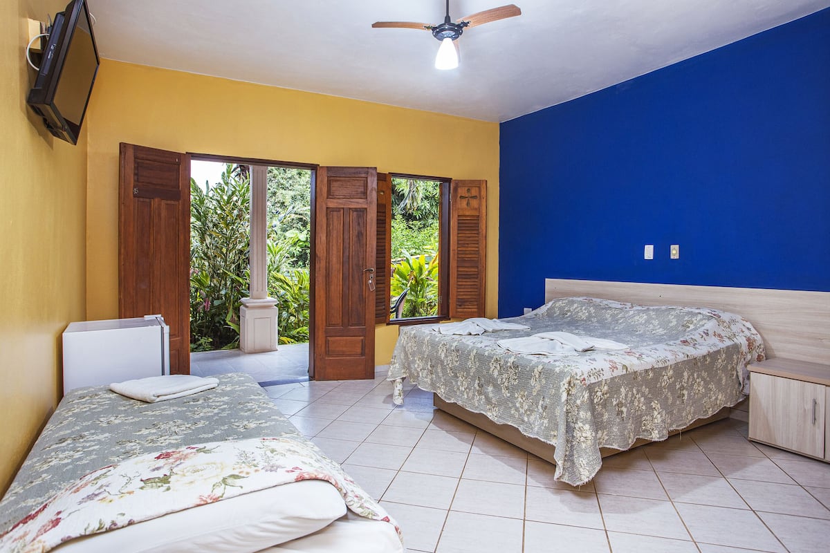 A bedroom with two beds, a ceiling fan, and a TV mounted on the wall.