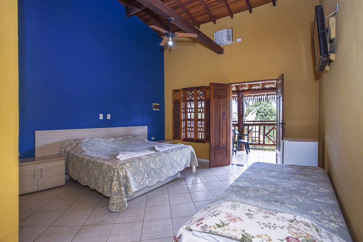 A bedroom with two beds, a ceiling fan, and a door leading to an outdoor area.