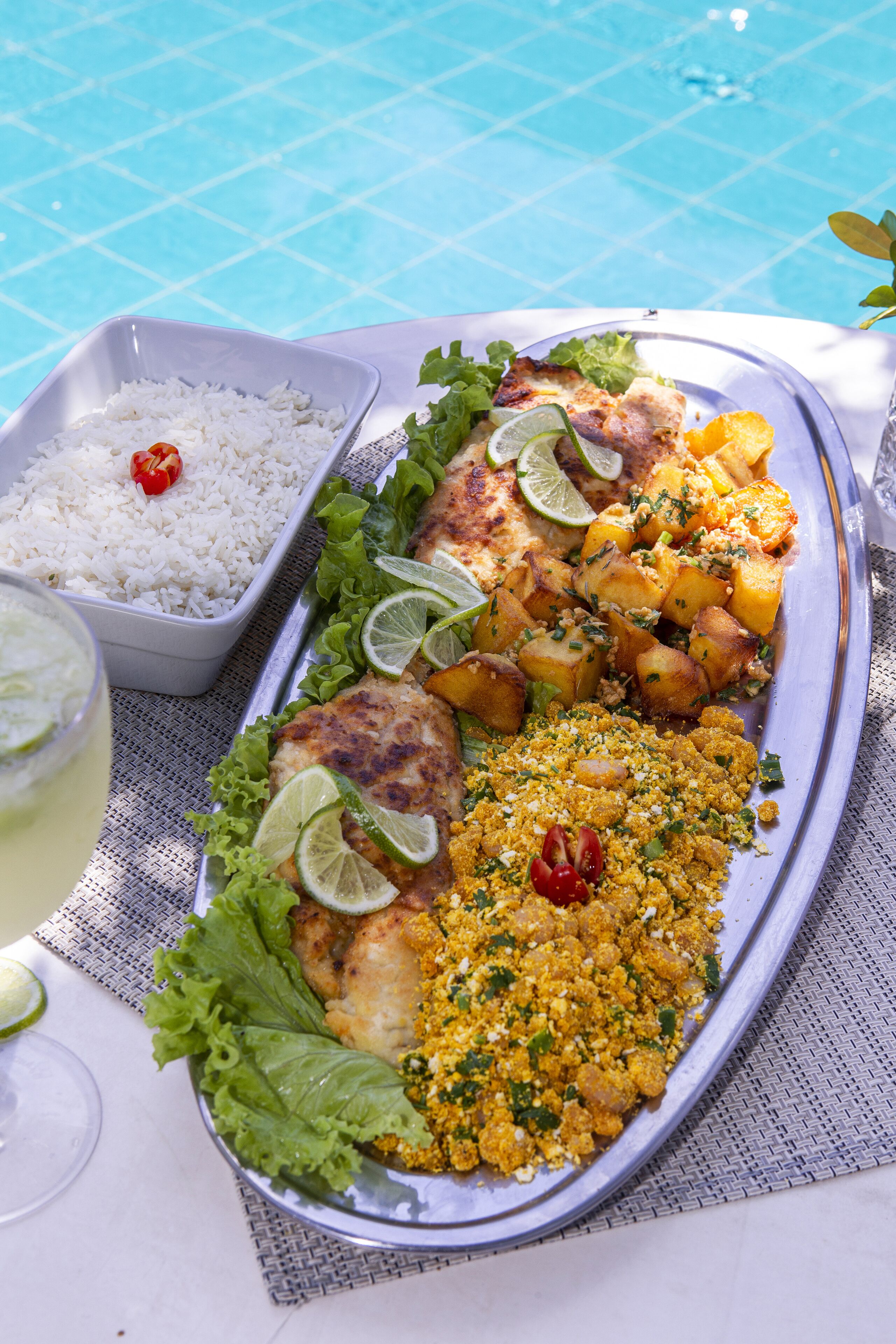 Uma refeição com arroz, peixe, batatas e uma salada acompanhando, servida em uma bandeja.