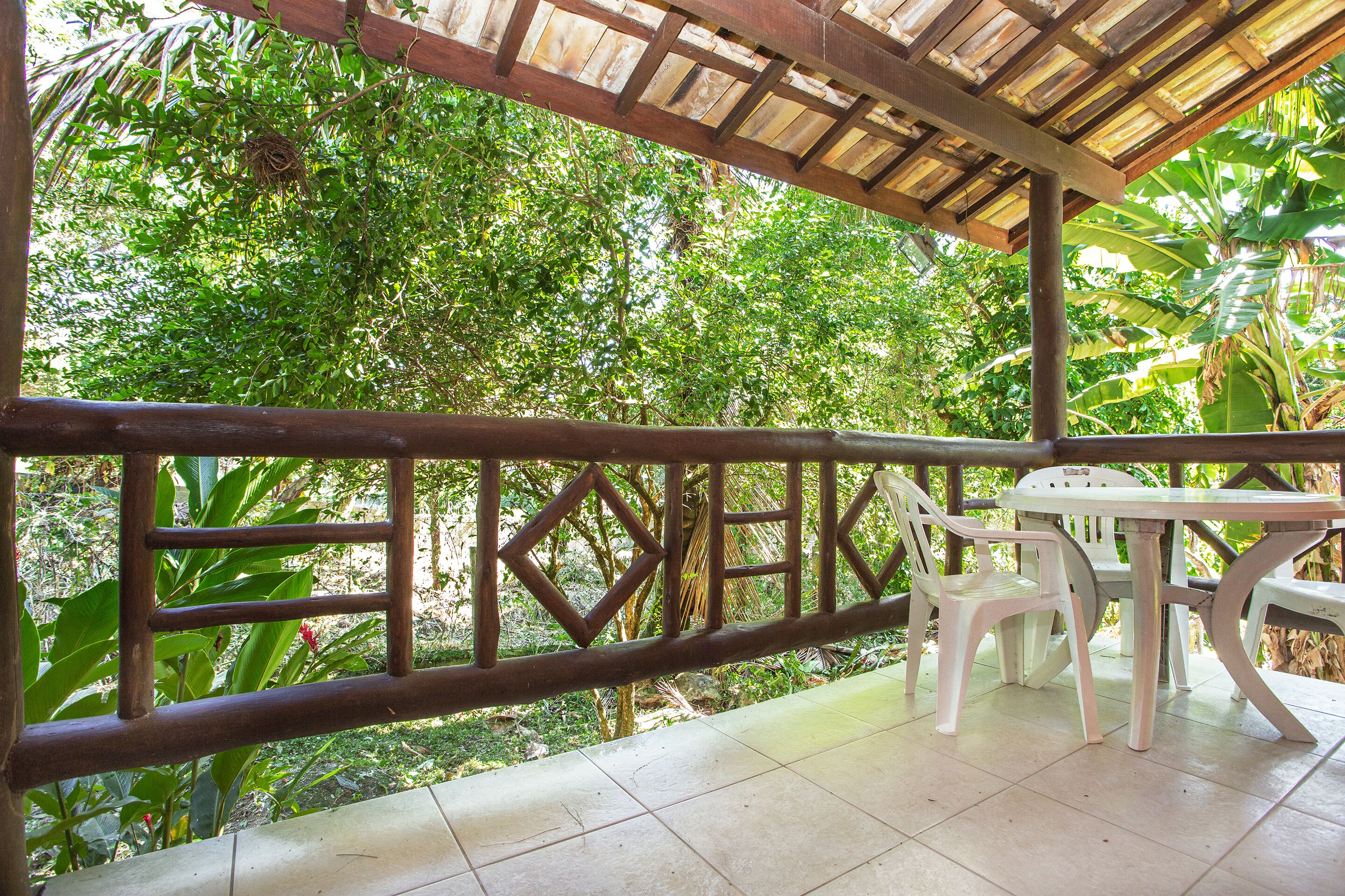 An outdoor patio with a wooden pergola, a white table, and plastic chairs.