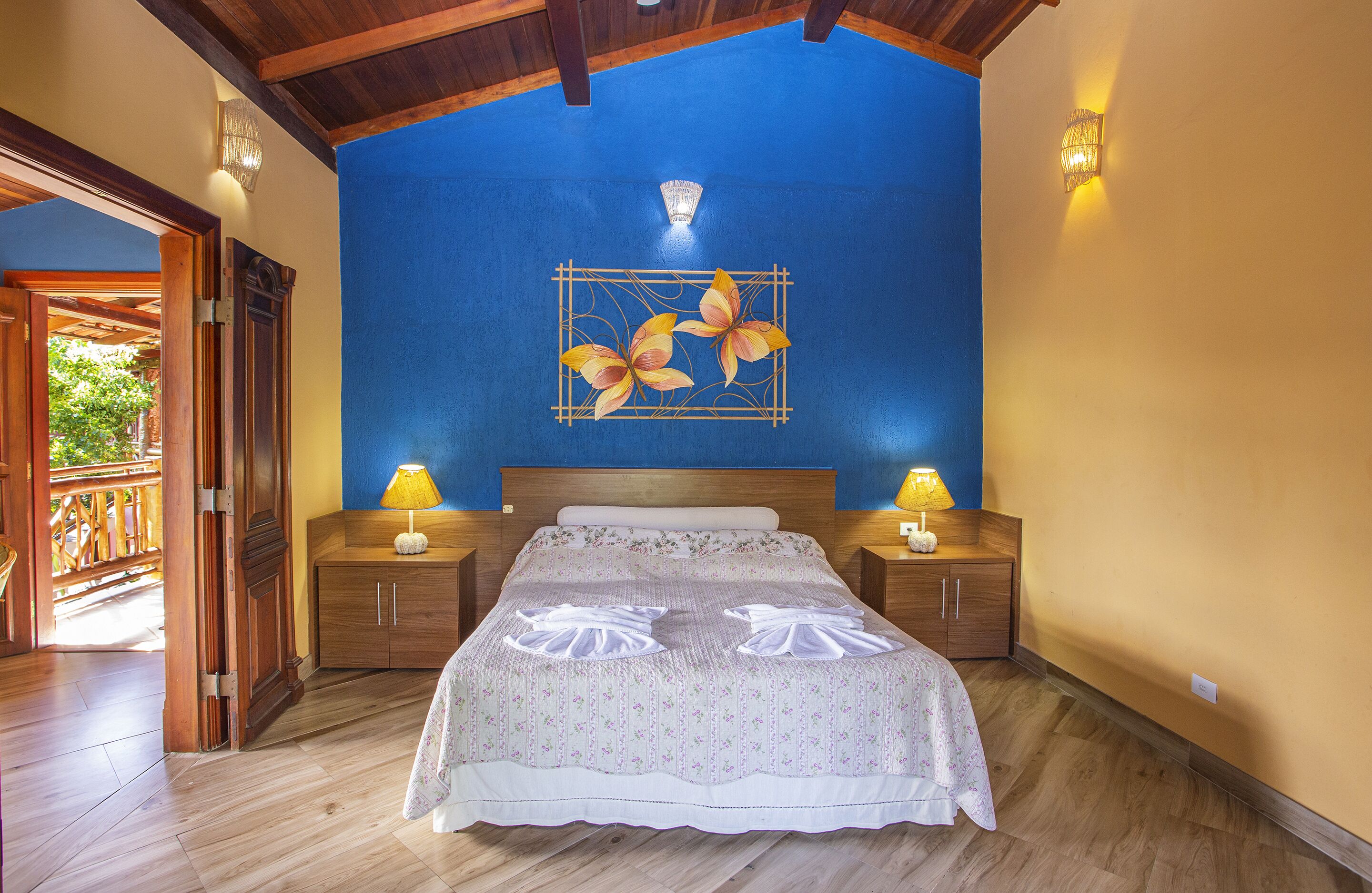 A bedroom with a large bed, wooden headboard, two bedside lamps, and a decorative wall piece.