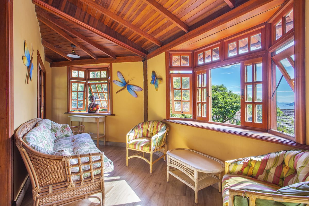 A room with wicker furniture, large windows, and a view of the outdoors.