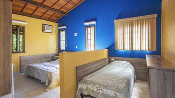 Una habitación con dos camas individuales, techo de madera y ventana con persianas.