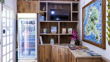 A wooden interior with a refrigerator, shelves with books and a map, and a television.