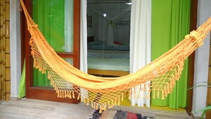 A room with a hammock, green curtains, and a bed with a mosquito net. - Bali Suites Itamambuca (Ubatuba)