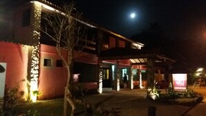 A building with a red facade, a covered entrance, and a signboard. - Bali Suites Itamambuca (Ubatuba)