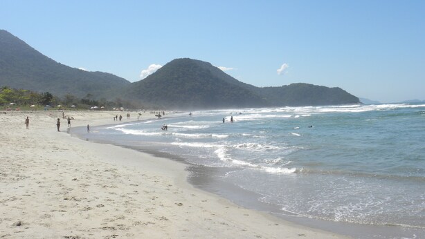 A beach with people, a sandy shore, and mountains in the background. - Bali Suites Itamambuca (Ubatuba)