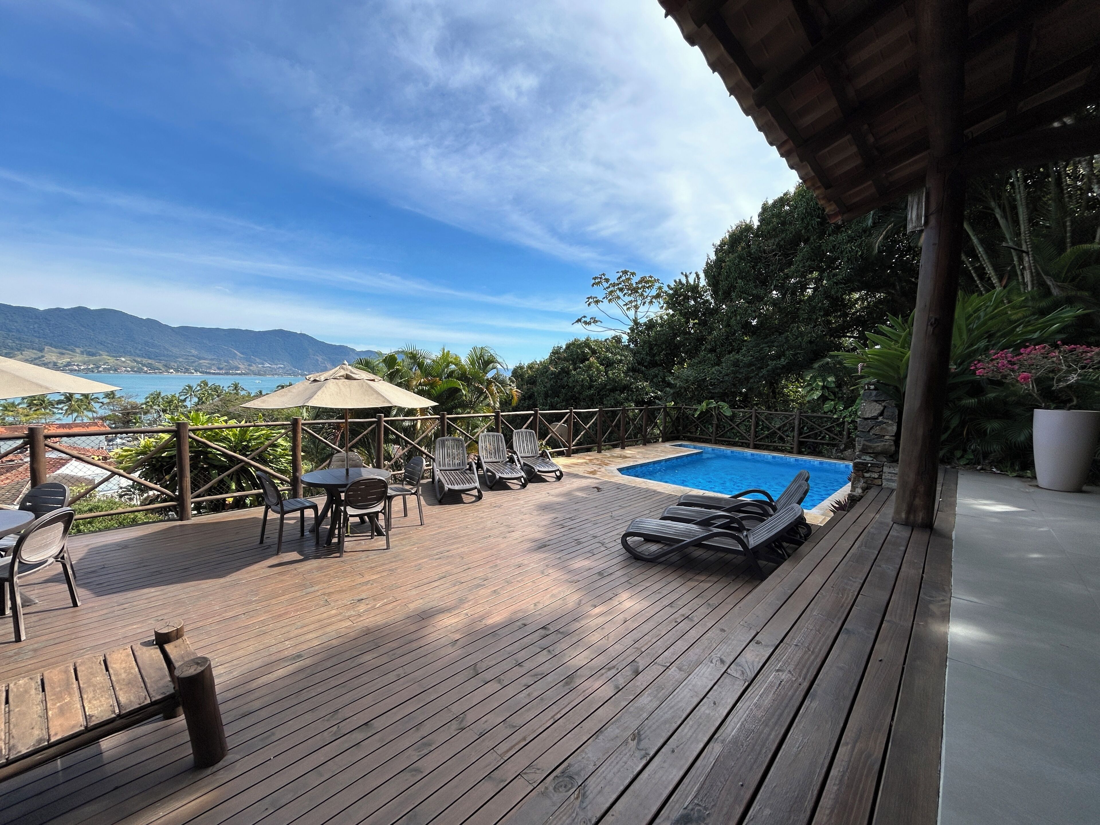 A wooden deck with a pool, lounge chairs, and a table.