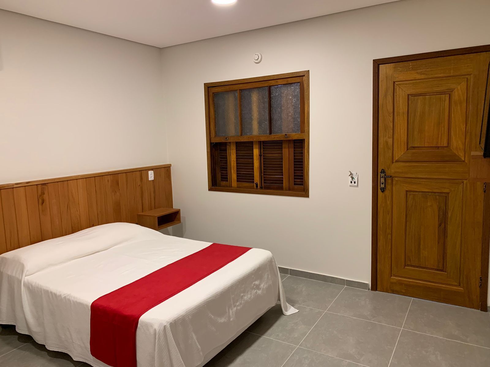 Una camera da letto con un letto, una finestra, una porta e un comodino.