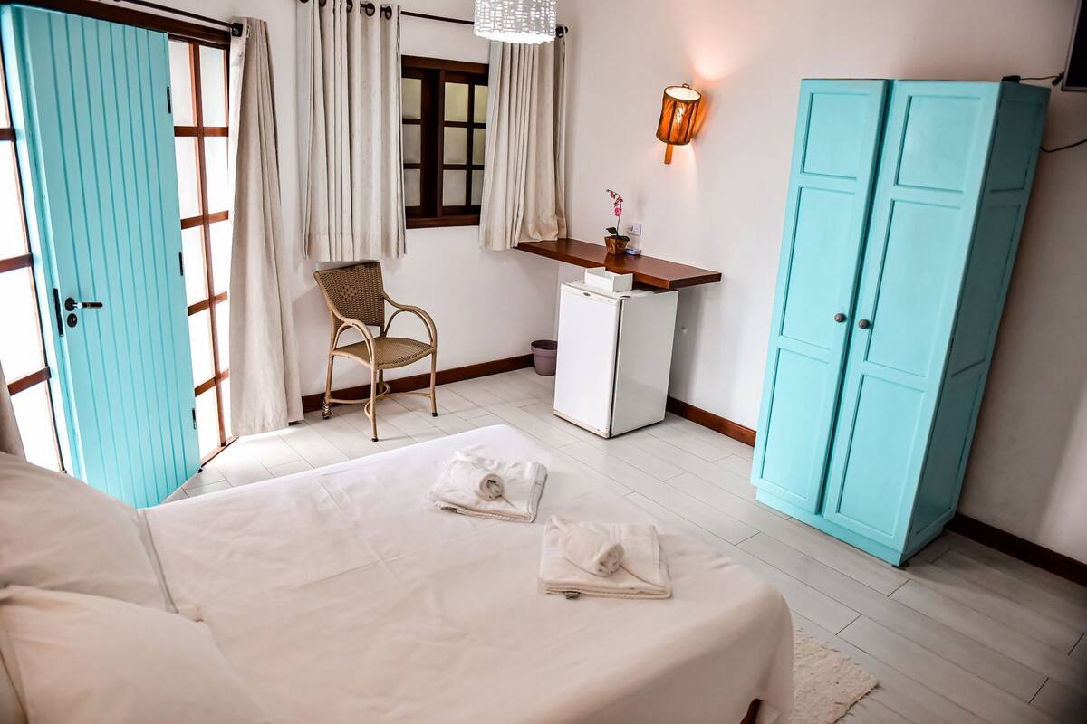 A bedroom with a bed, a desk, a chair, and a wardrobe.