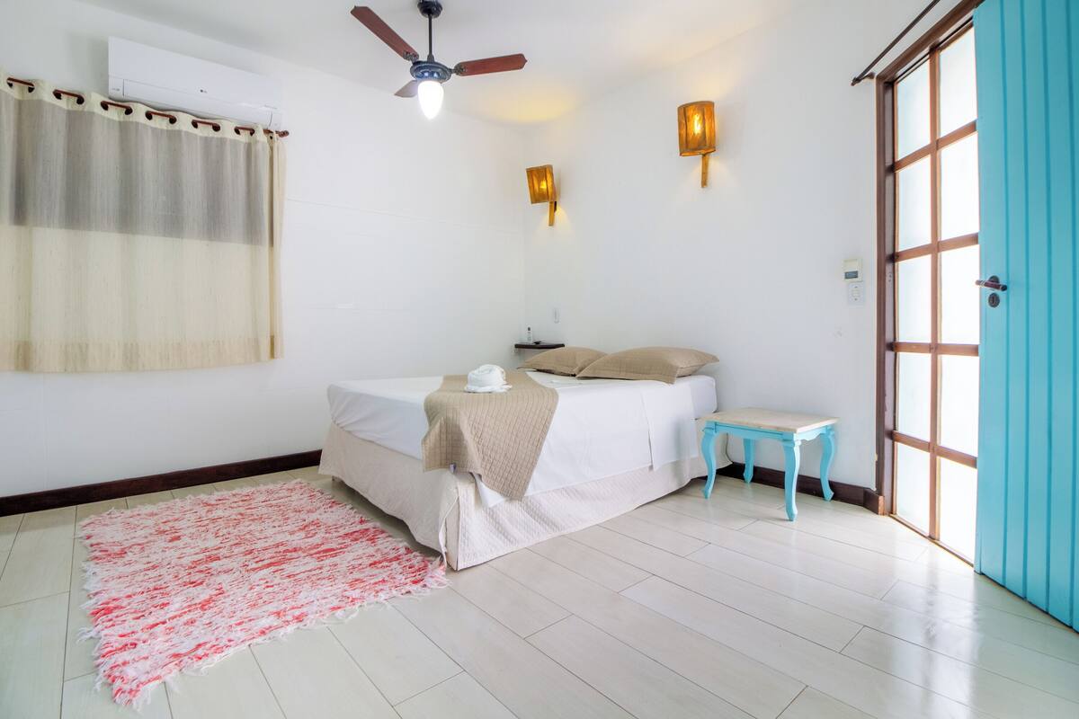 A bedroom with a bed, bedside table, and a window with a curtain.