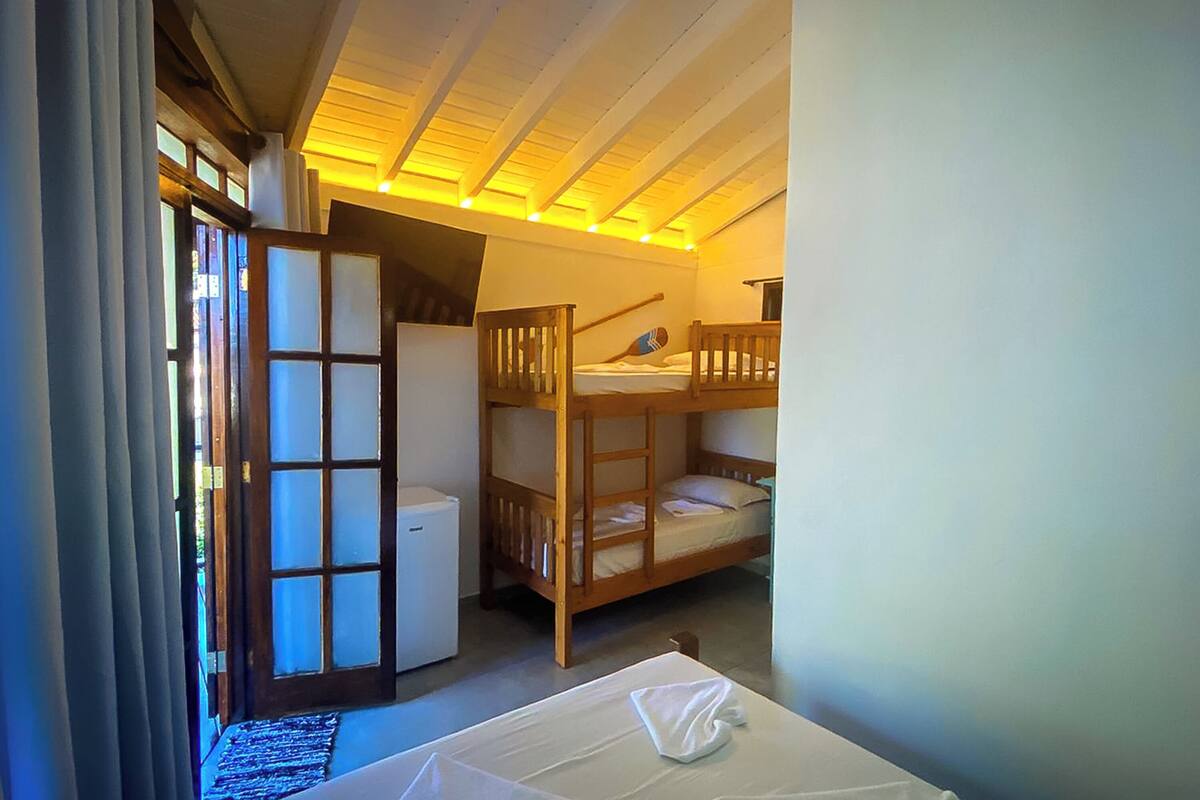 A room with bunk beds, a small refrigerator, and a sliding door leading to another room.