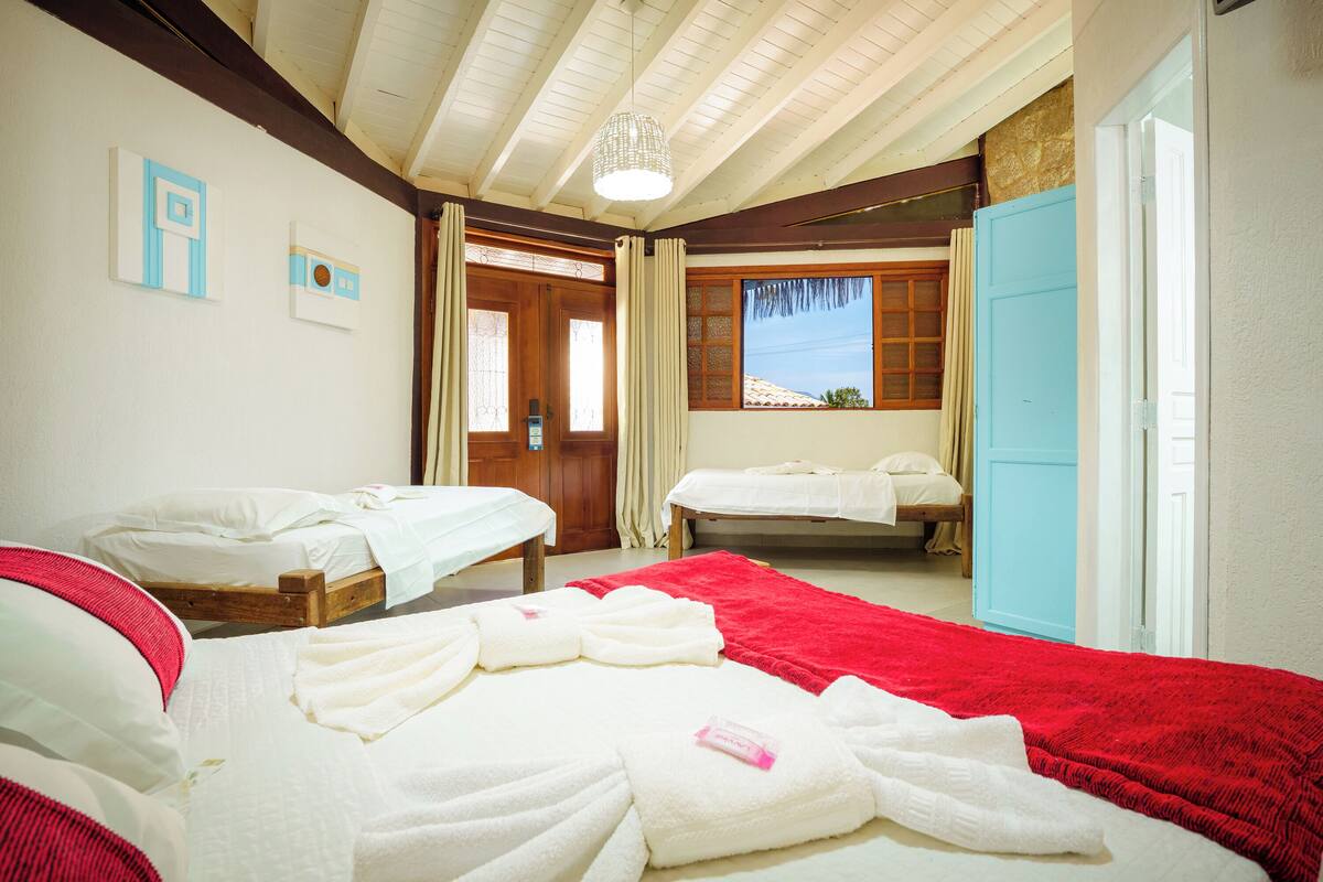 A hotel room with two beds, a red blanket, and a wooden ceiling.