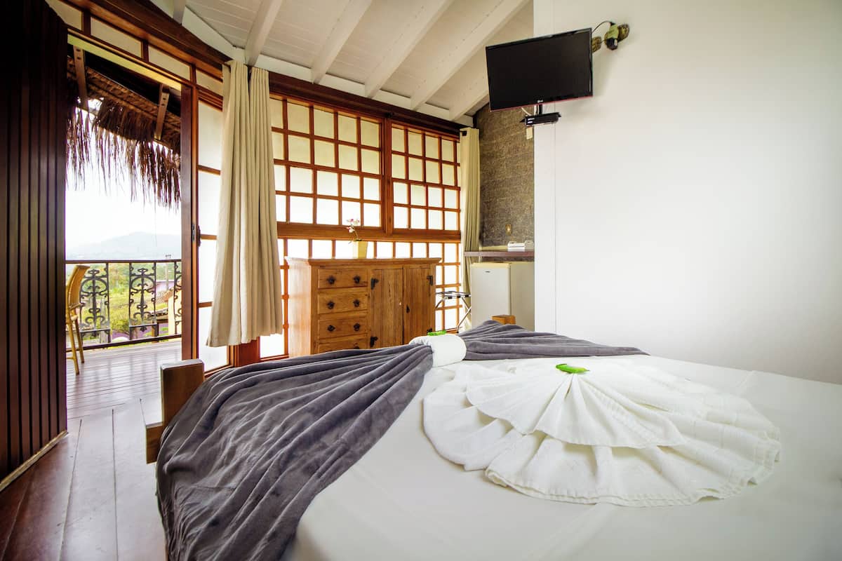 A traditional Japanese-style room with tatami flooring, a futon bed, sliding shoji doors, and a television mounted on the wall.