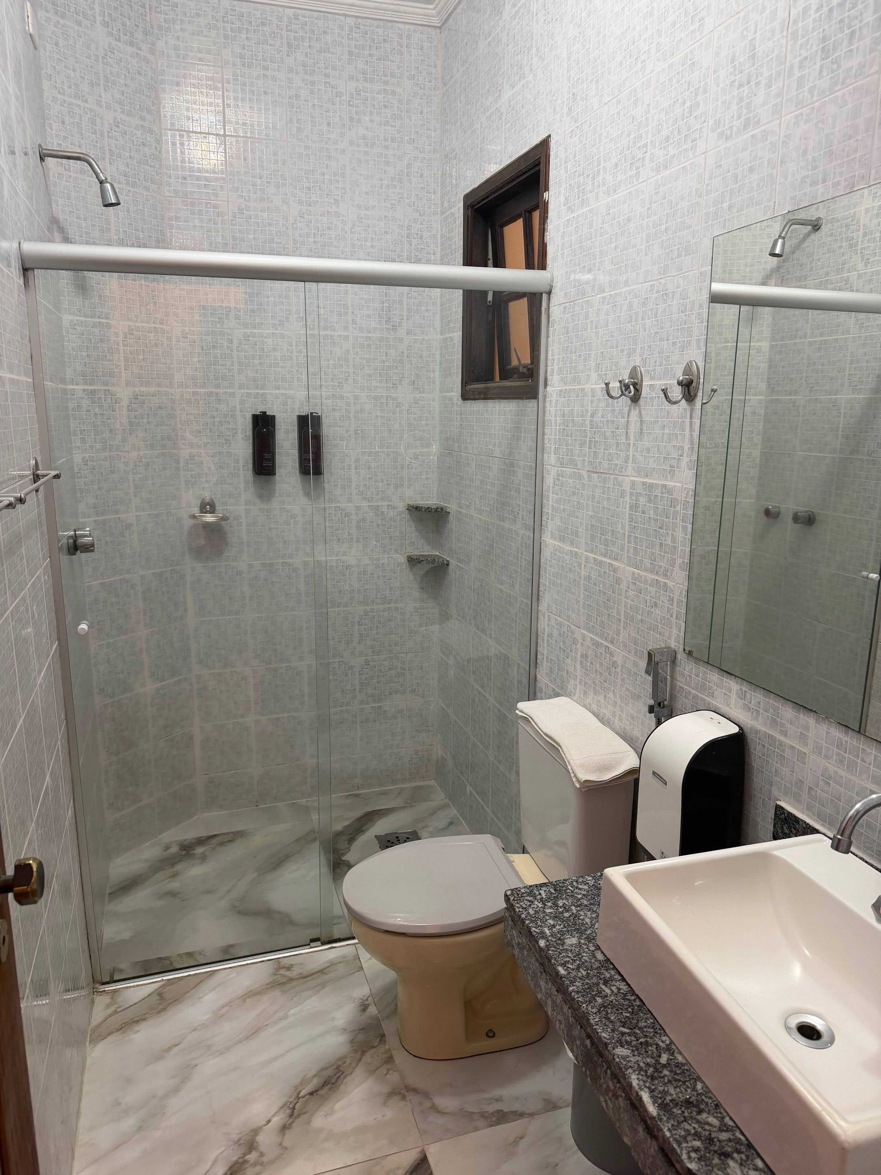 A bathroom with a glass-enclosed shower, a toilet, a sink, and a mirror.