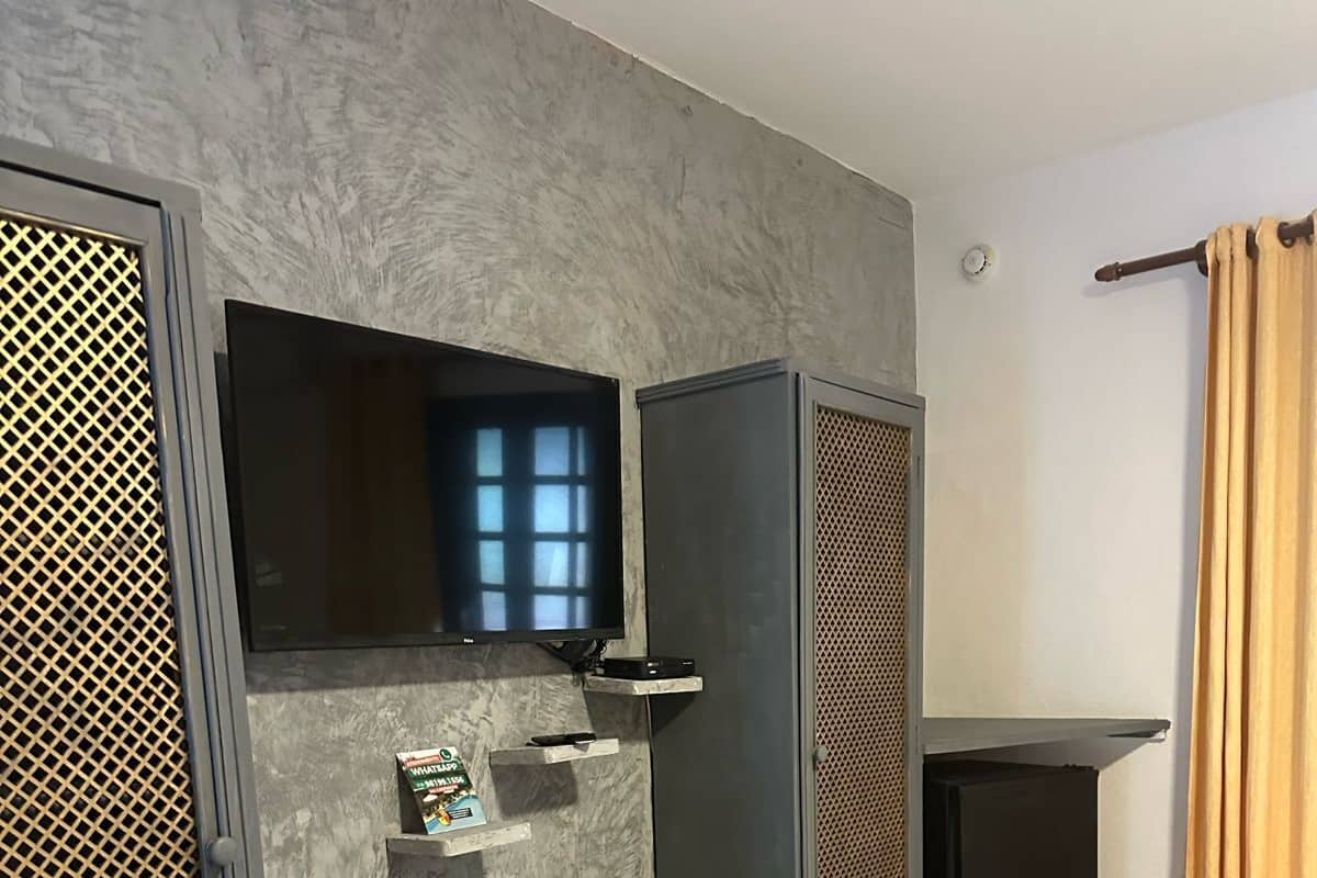 A modern room with a built-in desk, a chair, a television, and a small shelf with items.