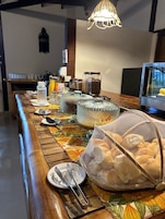 Montaje de bufé con diversos recipientes de comida, una máquina de café y un lámpara colgante.
