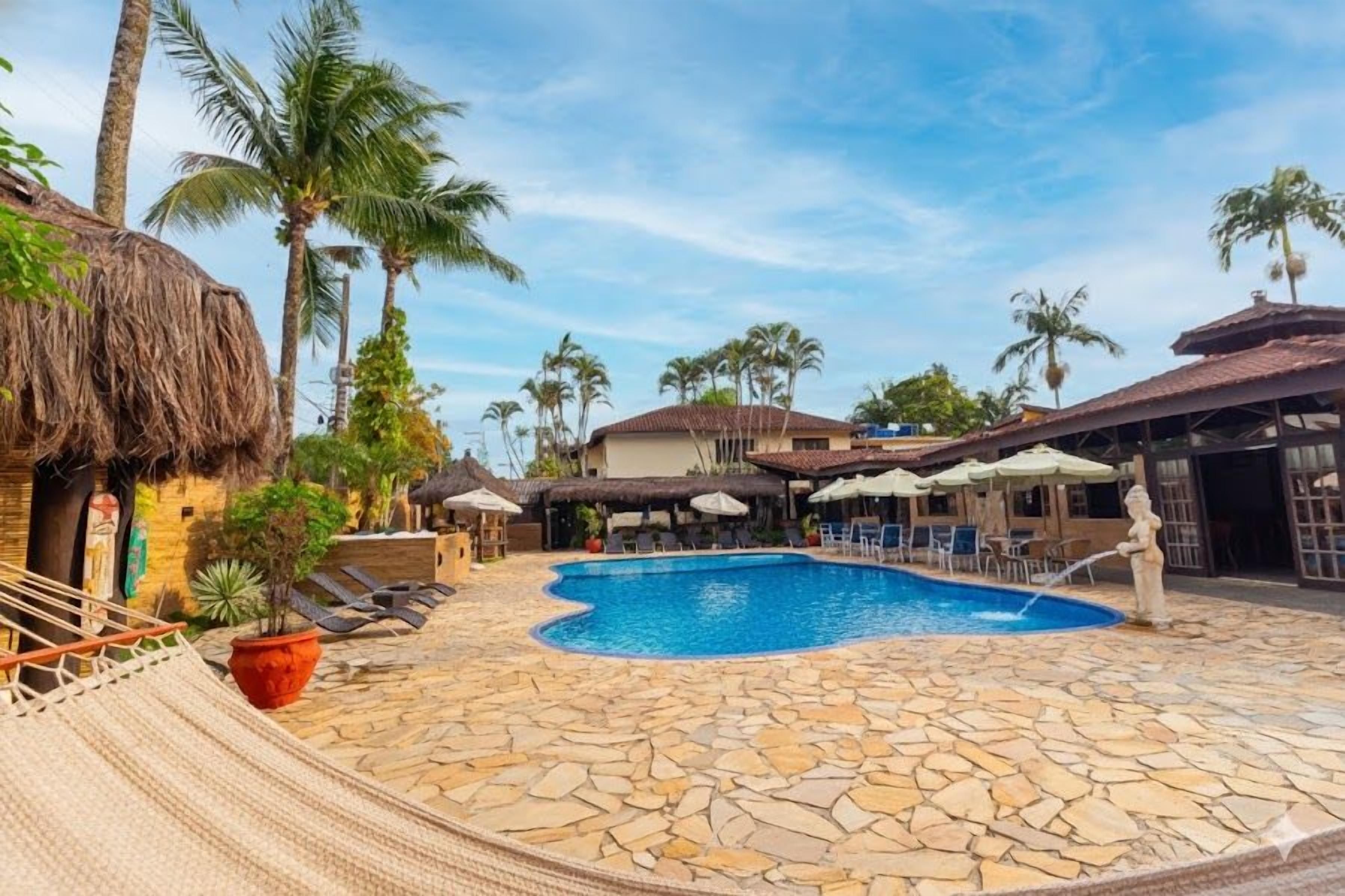 A pool area with lounge chairs, a hammock, and a statue.