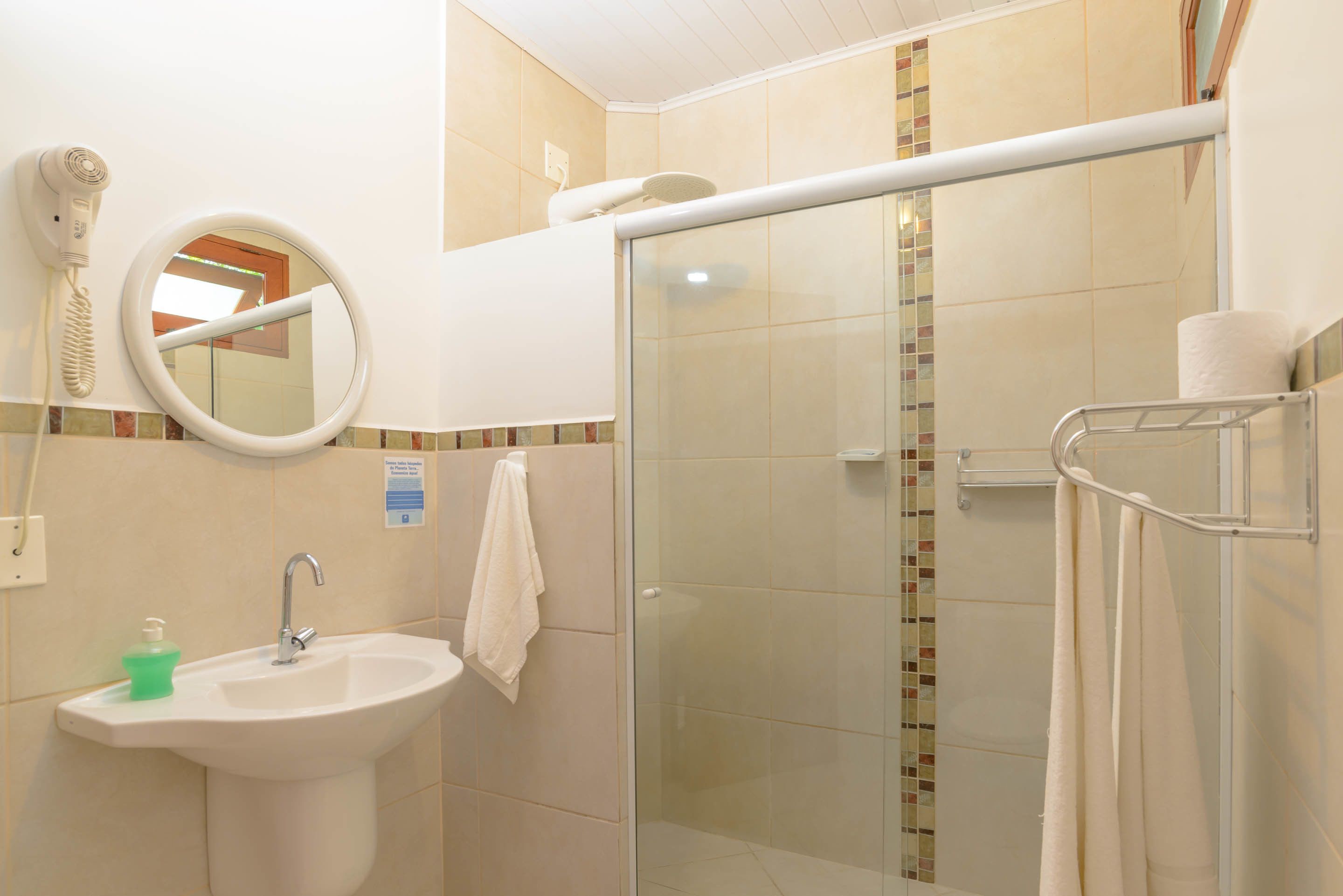 Un baño con lavamanos, espejo, toallero y cabina de ducha de vidrio.