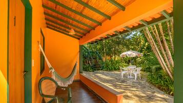 A covered patio with a hammock, chairs, and a table.