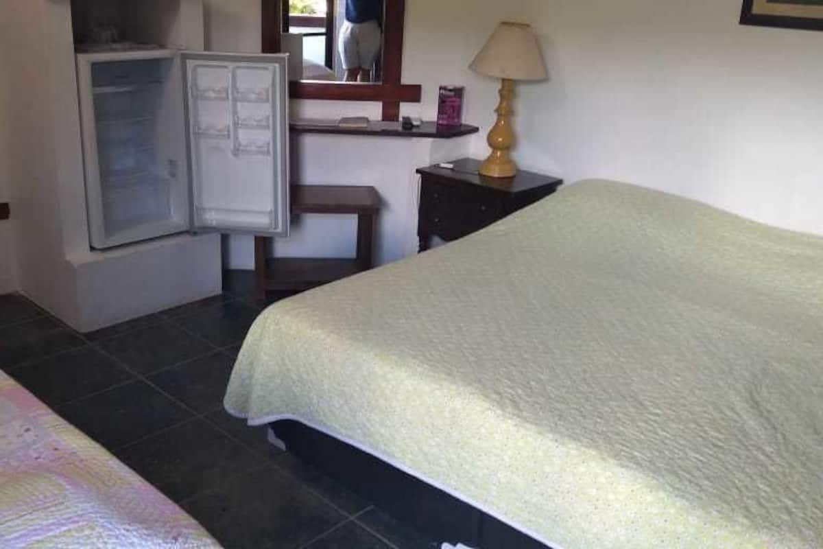 Un dormitorio con cama, un escritorio pequeño, un refrigerador y una lámpara.