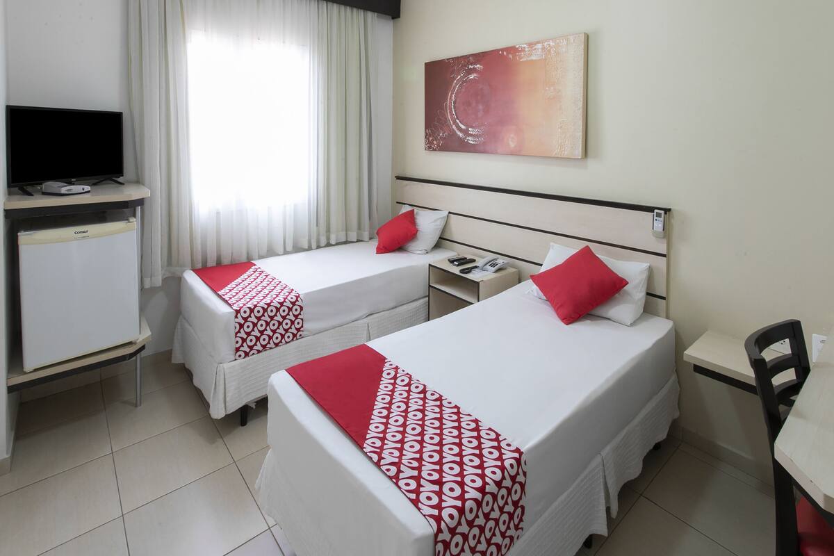 Habitació d'hotel amb dos llits, un escriptori, una televisió i un quadre a la paret.