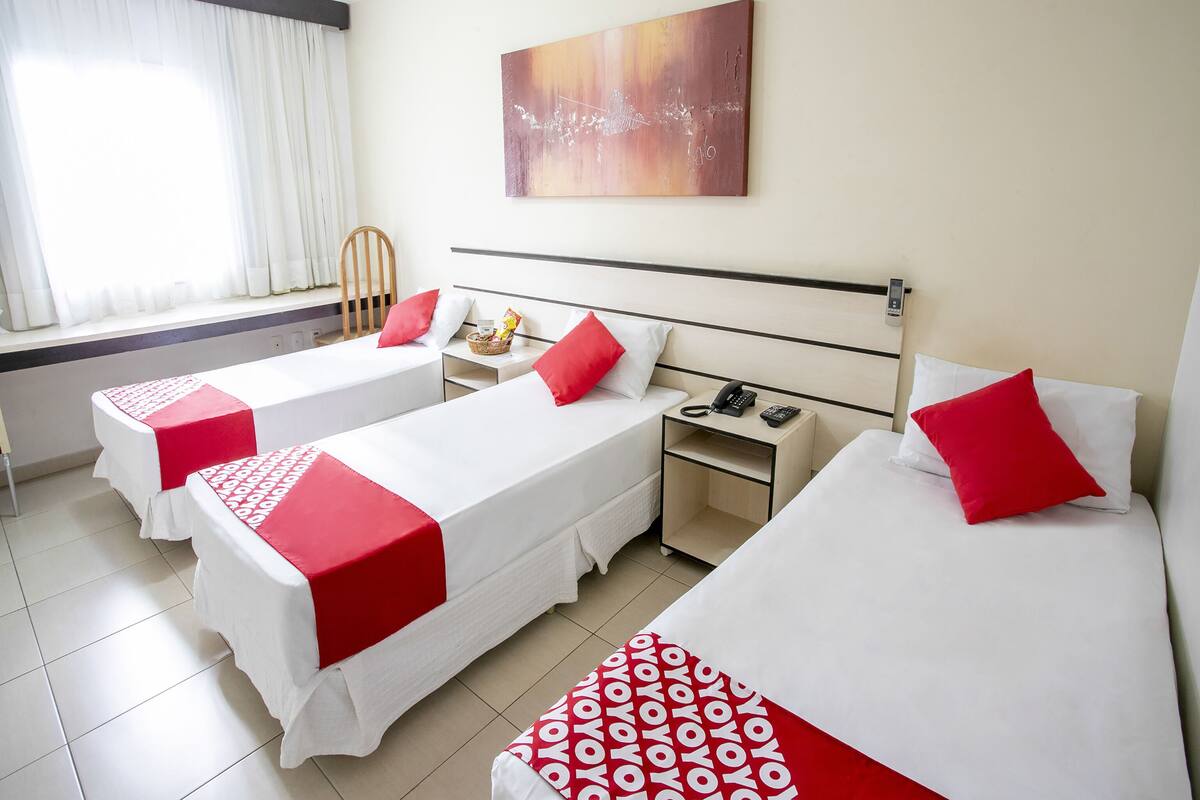 Habitació d'hotel amb dos llits individuals, una tauleta de nit, un telèfon i una finestra amb cortines.