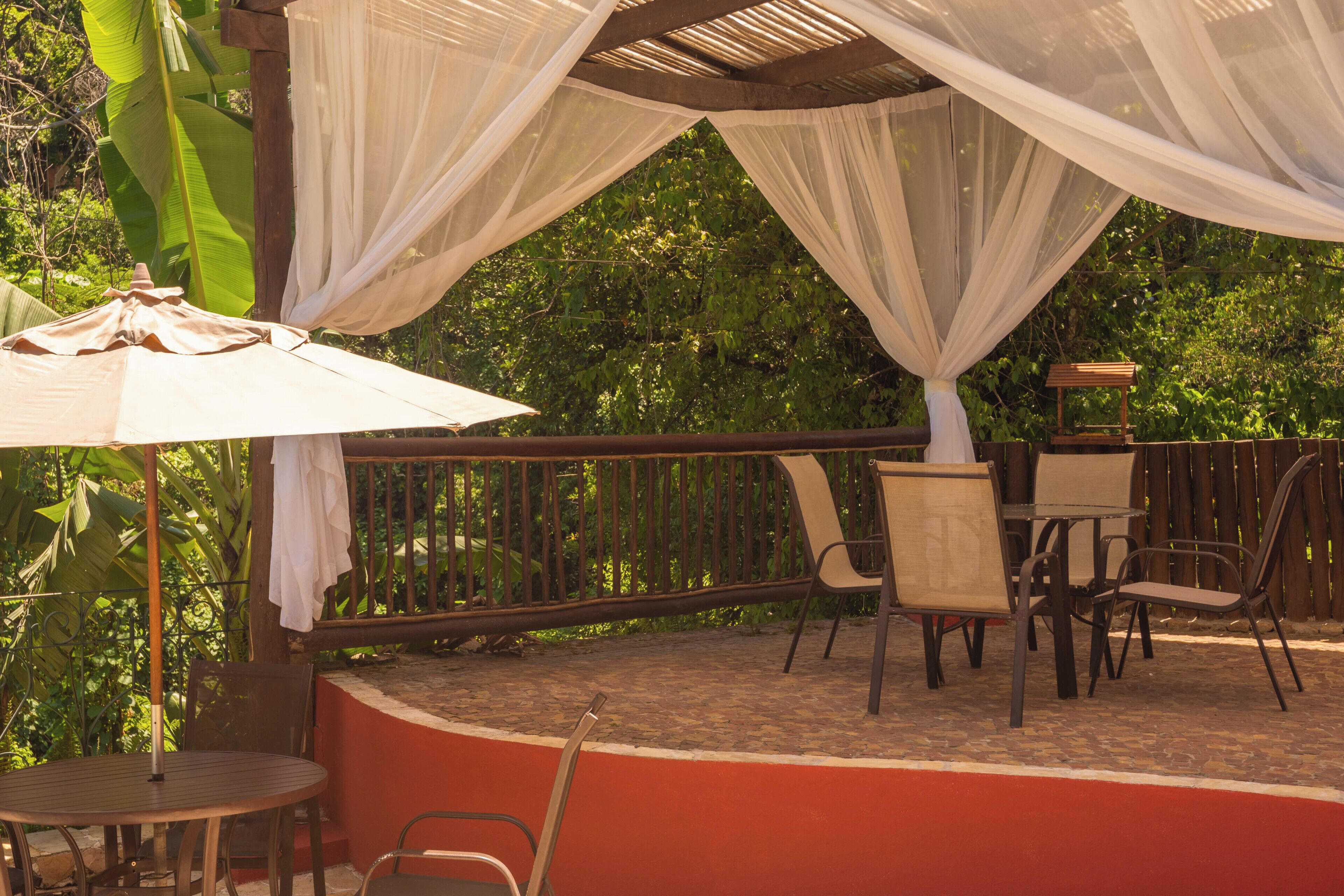 An outdoor patio with a round table, chairs, and a white canopy.