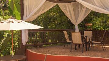 An outdoor patio with a round table, chairs, and a white canopy.