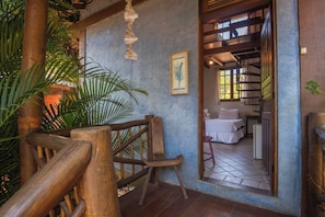 A wooden chair in a room with a tiled floor, a framed picture on the wall, and a staircase leading to another room. - Pousada Villaggio Assis (Ilhabela)