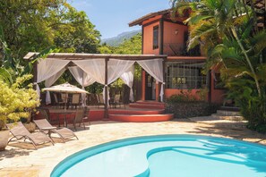 Una piscina al aire libre, sombrillas, sillones reclinables de piscina