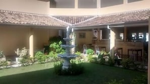 A courtyard with a central fountain, surrounded by greenery and a tiled roof structure. - Hotel Portal de Barequeçaba (São Sebastião)