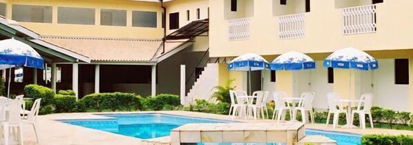 Una piscina al aire libre, sillones reclinables de piscina