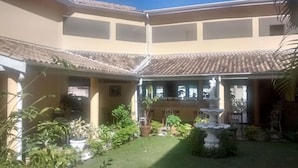 A courtyard with a tiled roof, a fountain, and various potted plants. - Hotel Portal de Barequeçaba (São Sebastião)