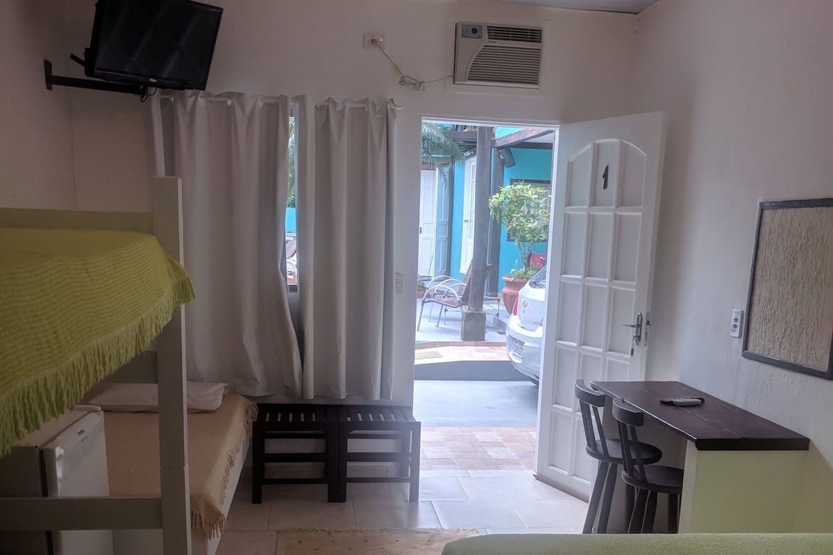Quarto com beliches, uma escrivaninha e ar condicionado.