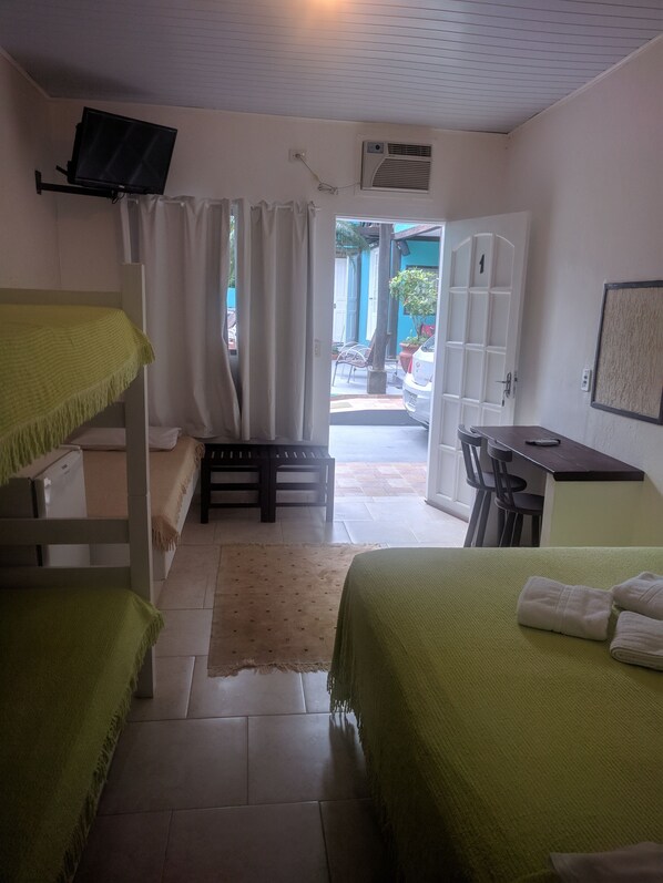 A room with bunk beds, a desk, and an air conditioning unit.