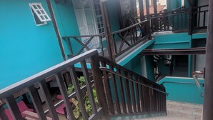 Una escalera con barandillas de madera que lleva a un edificio turquesa.