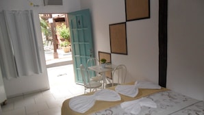 Habitación de hotel con cama, mesa, sillas, puerta y vista al exterior.