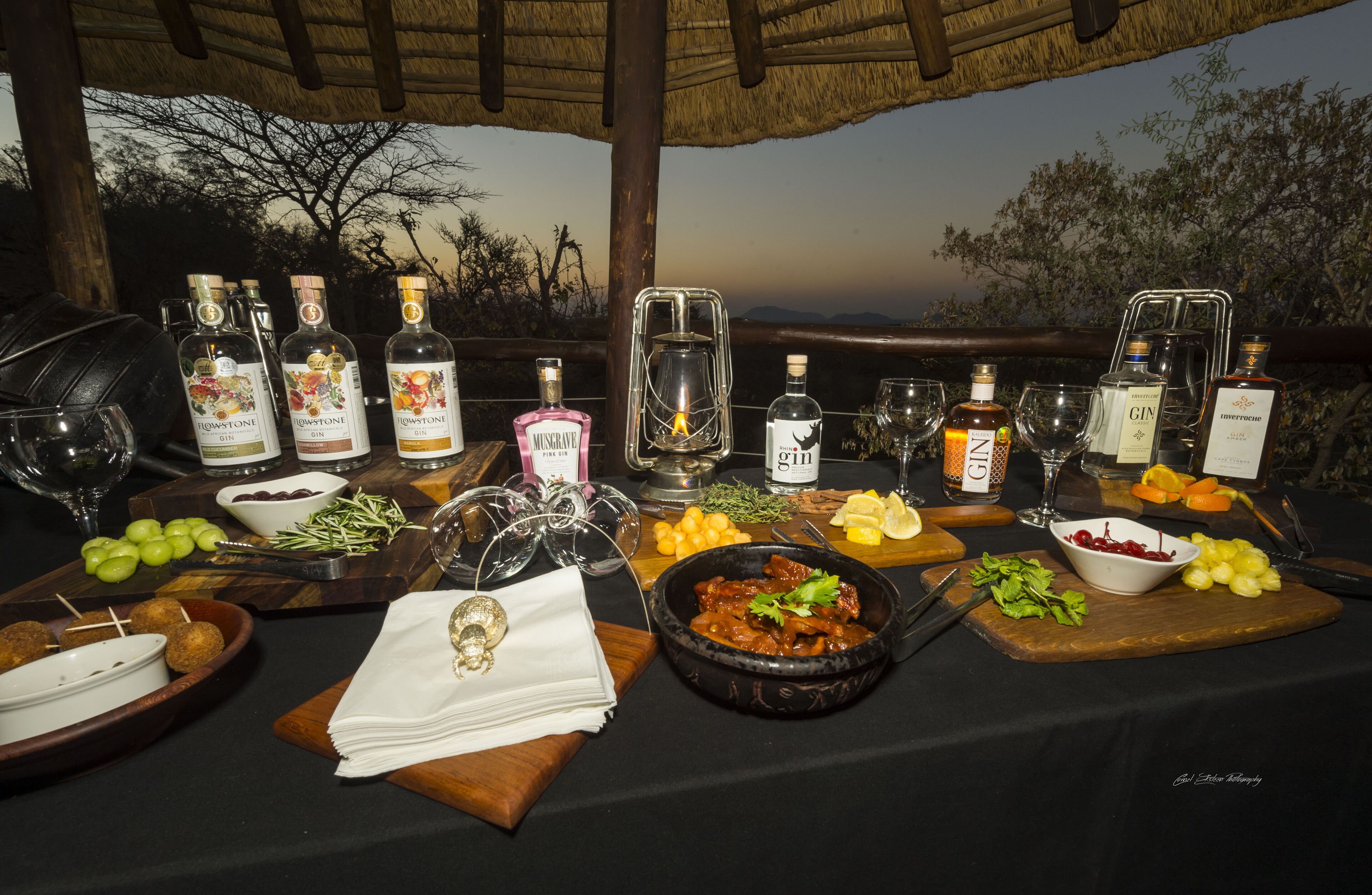 A table set for a meal with various bottles of alcohol, glasses, and food.