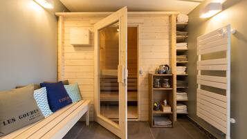 Een sauna met houten banken, een bank met handdoeken, een plank met handdoeken en een witte radiator.